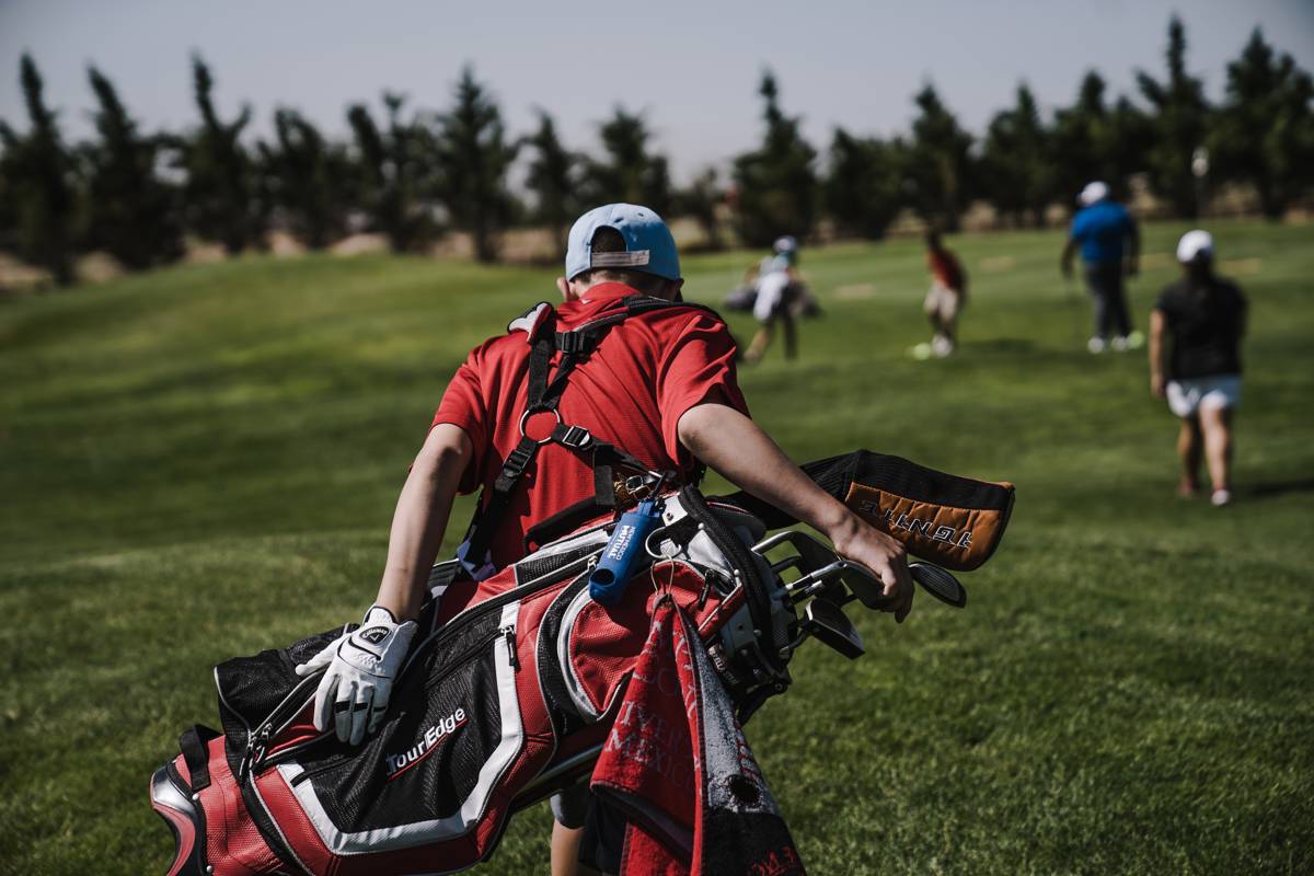 Man Walking Carrying Black And Red Golf Bag On Green Grass 1325681
